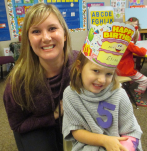 An image of a woman with her child. The child is wearing a paper crown. They are both smiling.