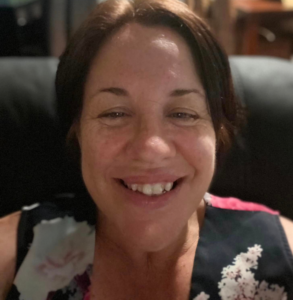 A woman with brown hair smiling and looking at the camera.