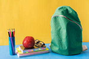 A green backpack, books, pencils, and an apple are shown as a back-to-school theme.