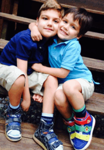 a pair of brothers hugs each other while posing for a picture