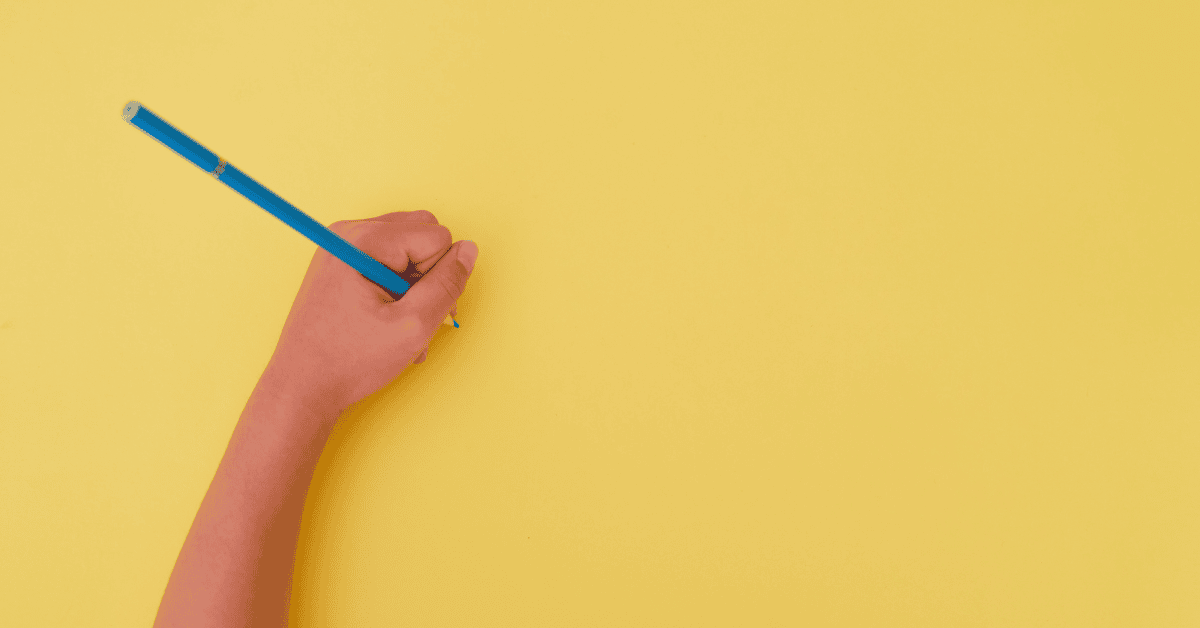Website – Blog Post Image 1200 x 630 A child holding a blue pencil with one hand against a yellow background.